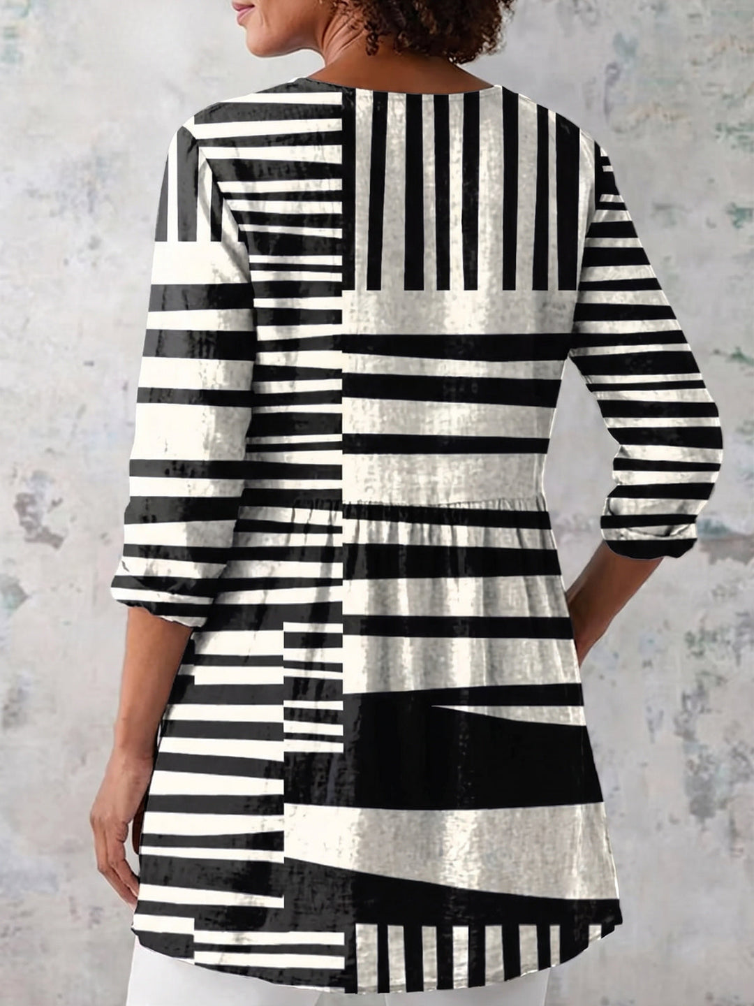 Back view of a woman wearing a geometric patterned long V-neck blouse