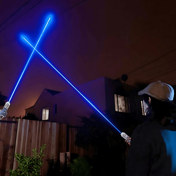 Person holding high power blue laser pointer projecting a bright beam outdoors at night