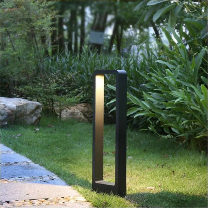 Sleek black outdoor garden lamp placed in green landscaping