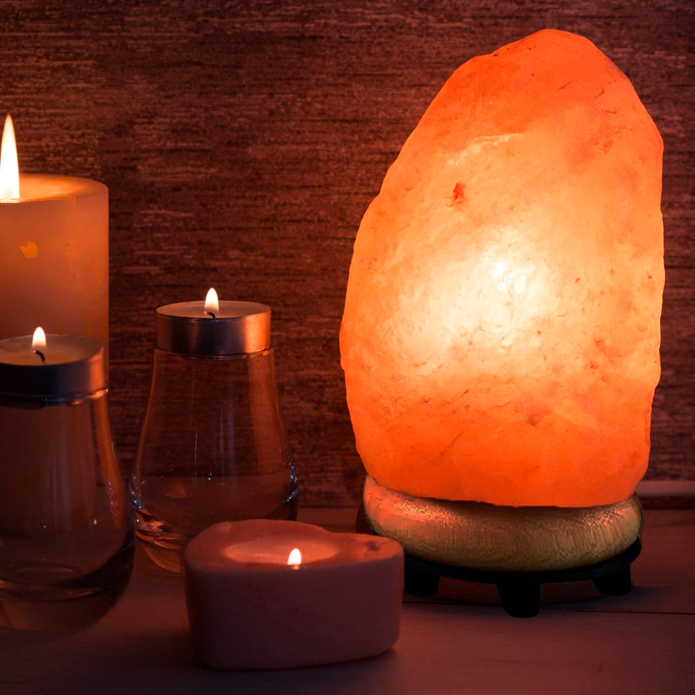 Lit Himalayan salt lamp glowing warmly next to candles on a table