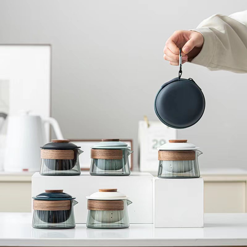 Hand holding the dark blue travel case for the portable tea set