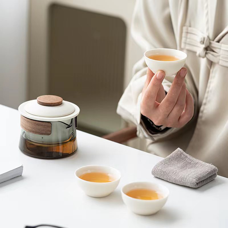 Person pouring tea into a ceramic cup from the portable teapot