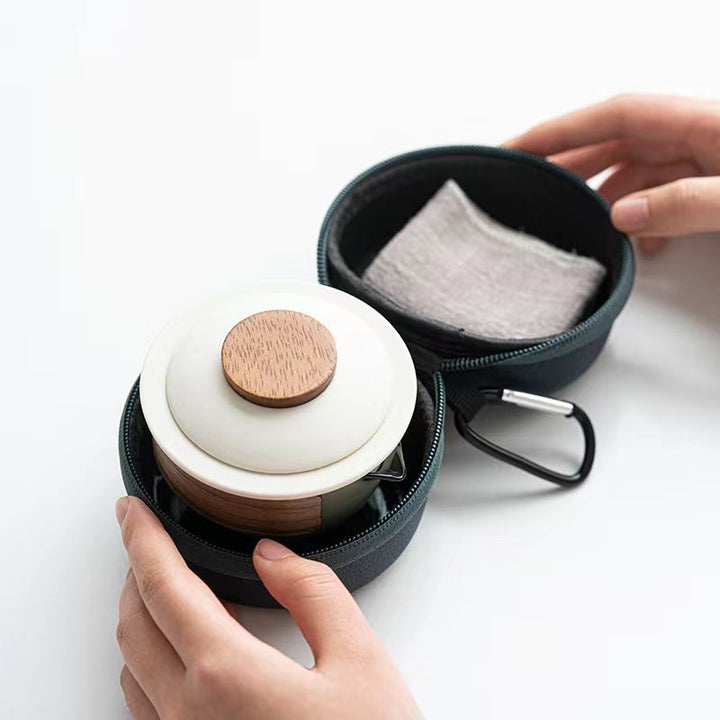 Open travel case revealing the nested ceramic teapot and tea cloth inside