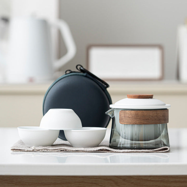 Ceramic travel tea set including small cups and teapot arranged neatly on a surface