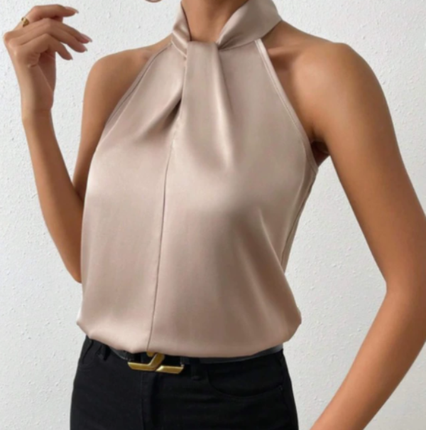 Model wearing a gold sleeveless twist-neck satin blouse paired with black pants