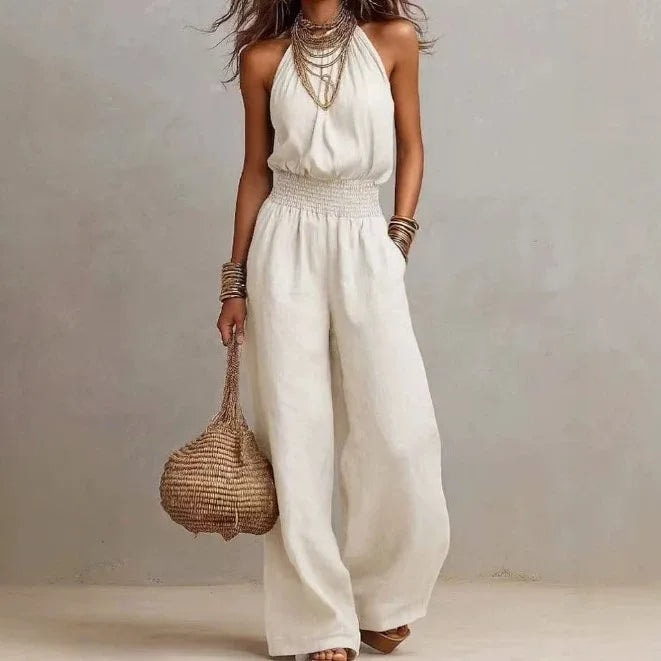 Woman wearing a white halter neck wide leg jumpsuit with a smocked waist