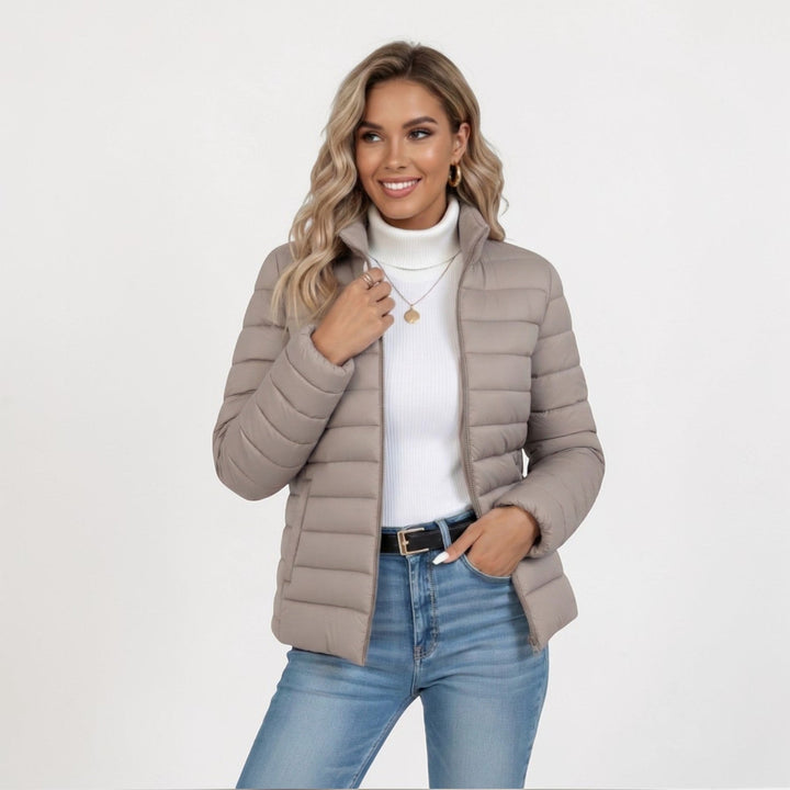 Blonde model wearing a beige quilted zip jacket with jeans and a turtleneck