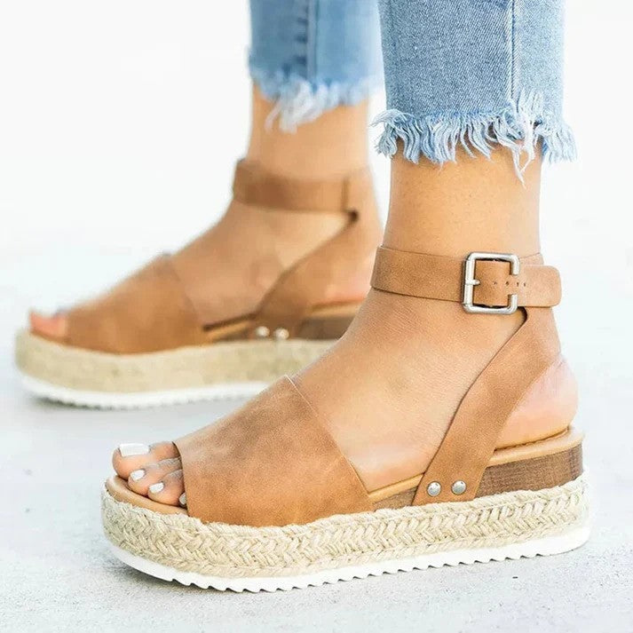Women wearing brown cushioned espadrille wedge sandals with an ankle strap buckle