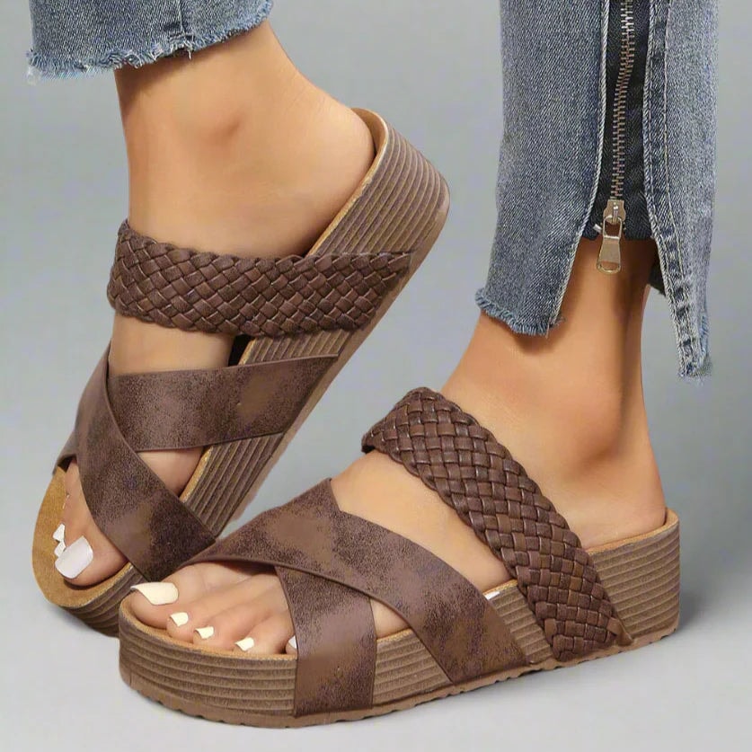 Close-up of brown woven crisscross platform wedge sandals worn with distressed jeans