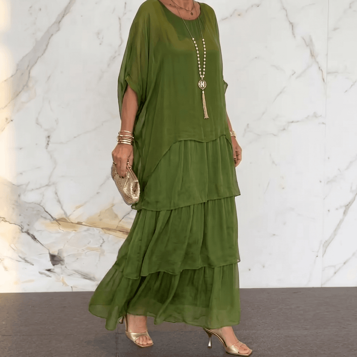 Woman wearing olive green tiered chiffon midi-to-maxi dress with batwing sleeves