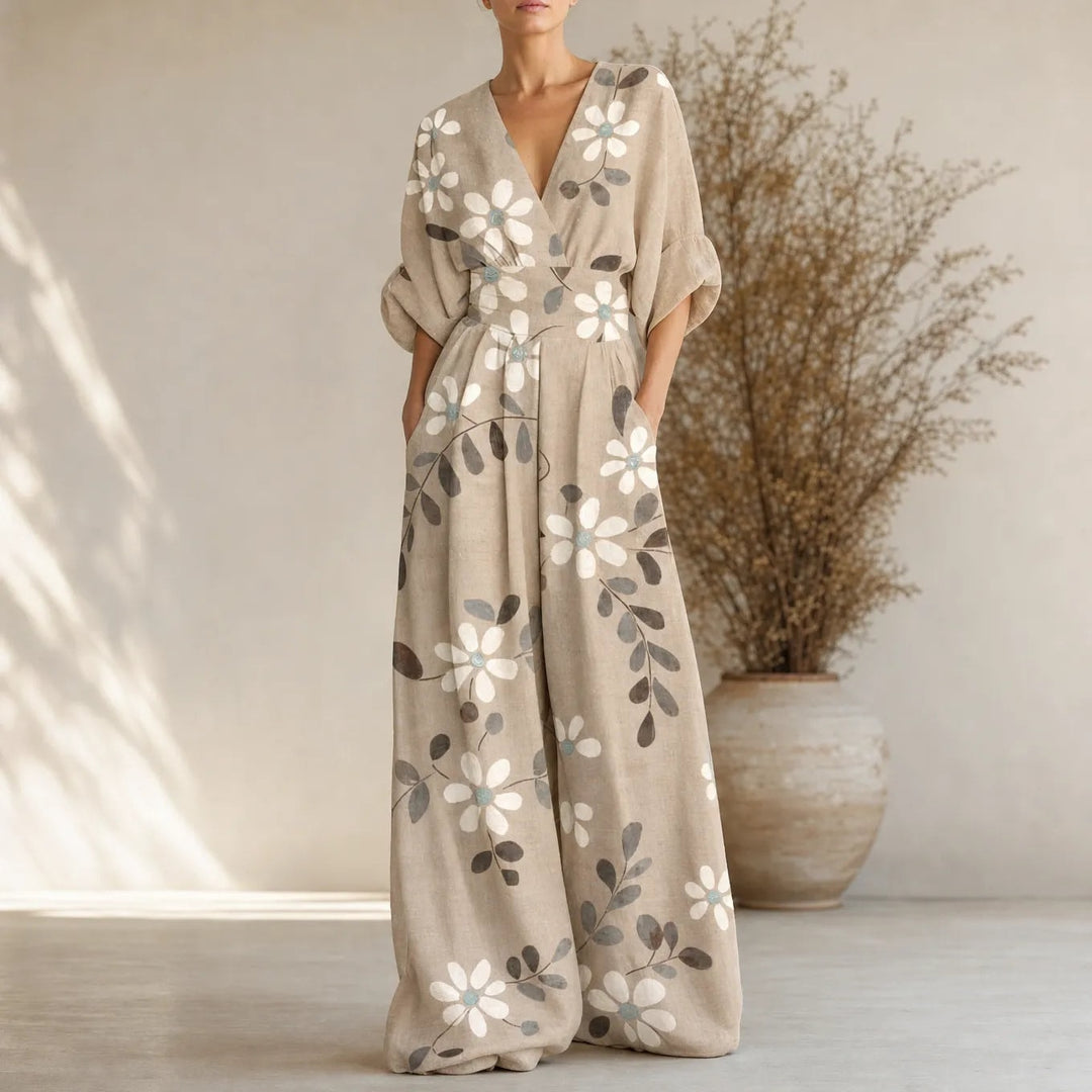 Model standing in neutral studio wearing a cream floral wide leg jumpsuit