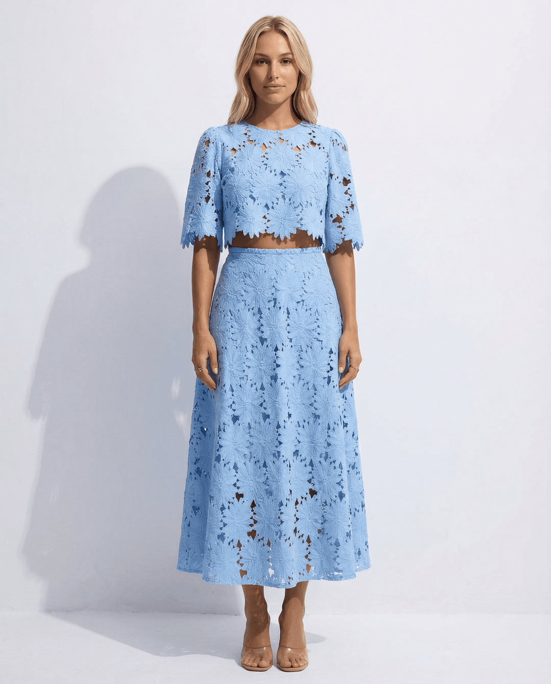 Front view of a blonde model wearing a light blue floral lace two-piece midi dress with short sleeves.