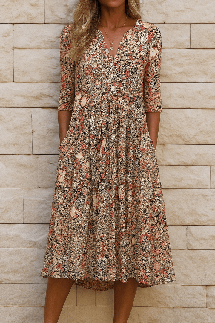 Woman wearing orange floral V-neck midi dress with pockets against a stone wall