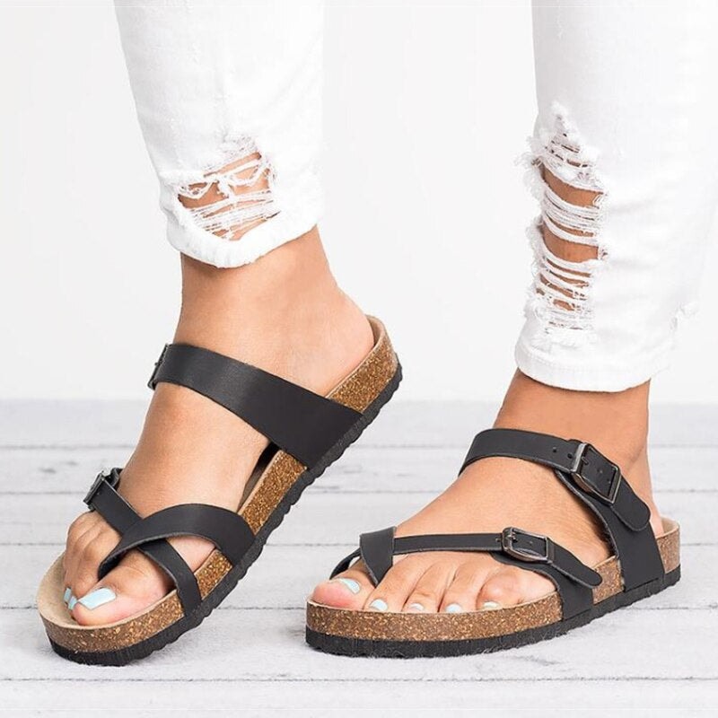Woman wearing black cushioned sandals with adjustable buckle straps and ripped white jeans