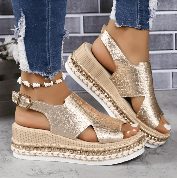 Model wearing metallic gold wedge platform sandals with textured straps and a woven espadrille sole