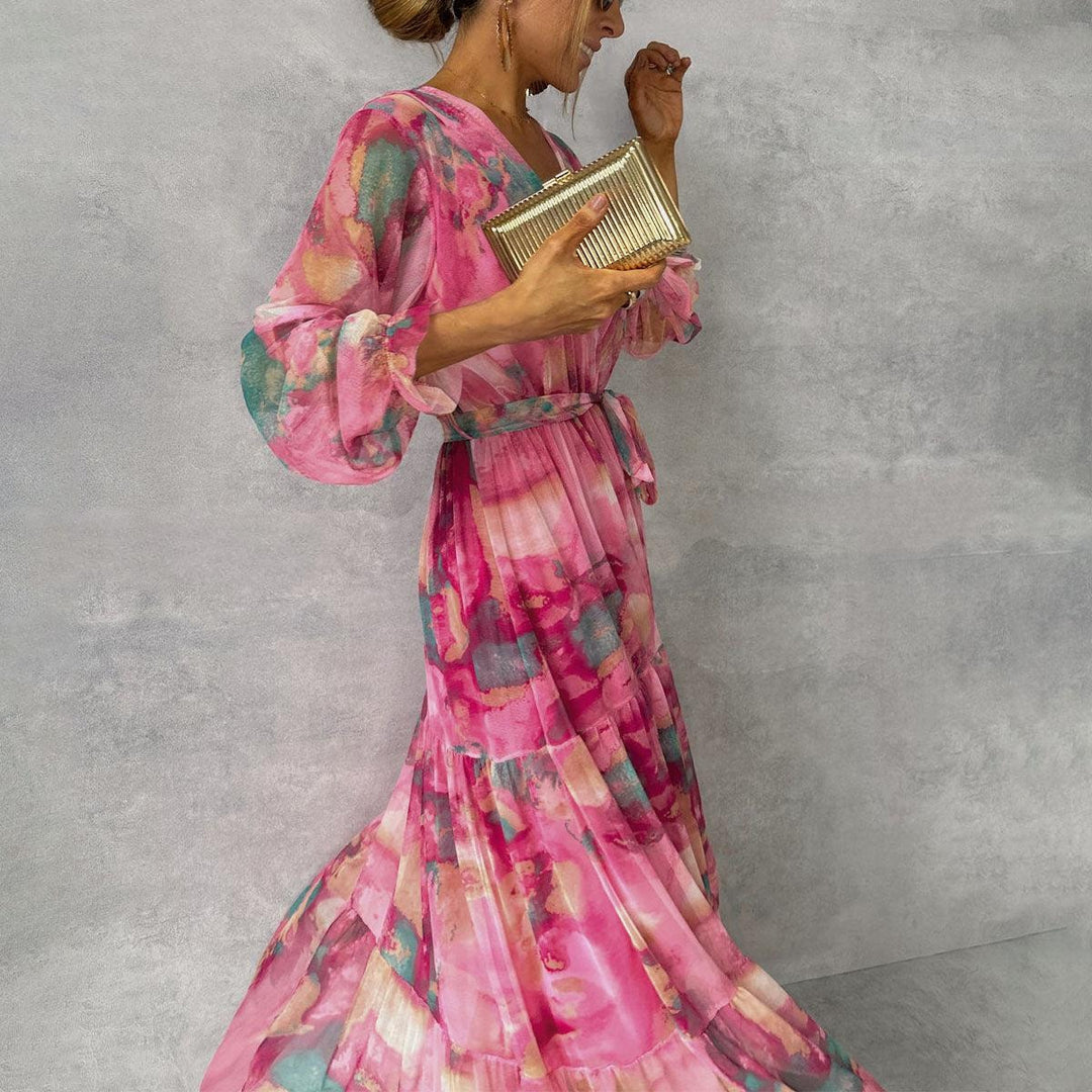 Model posing in a pink floral wrap maxi dress holding a gold clutch
