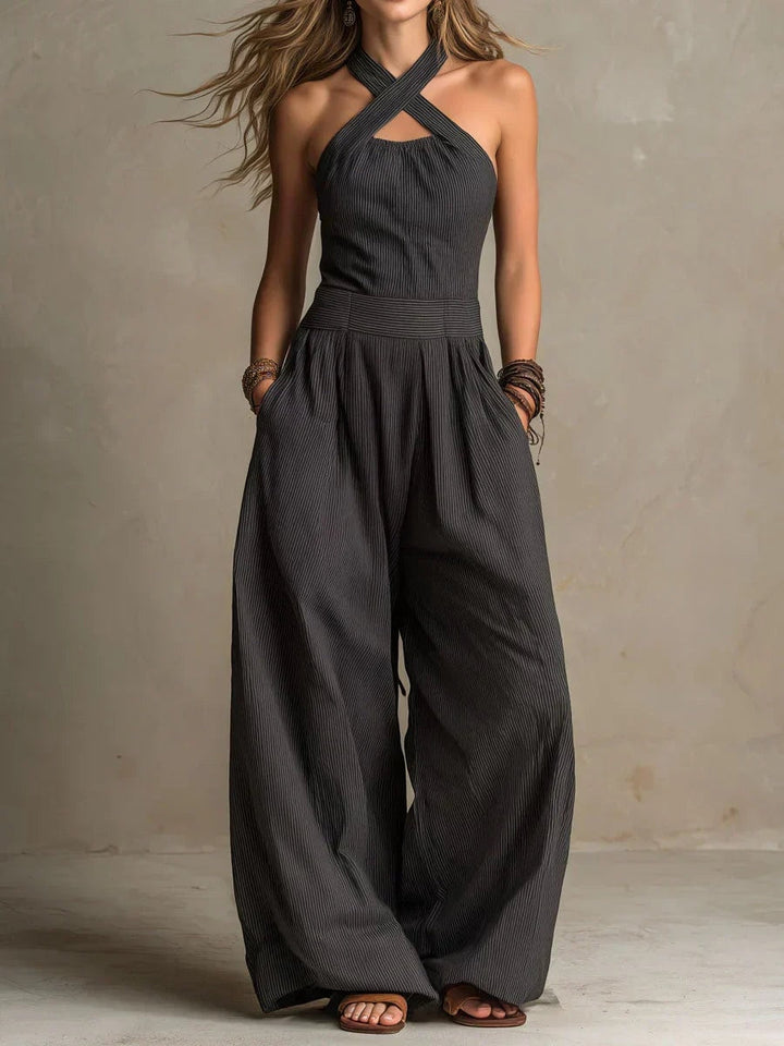 Woman wearing a black cross-neck halter wide-leg jumpsuit with side pockets