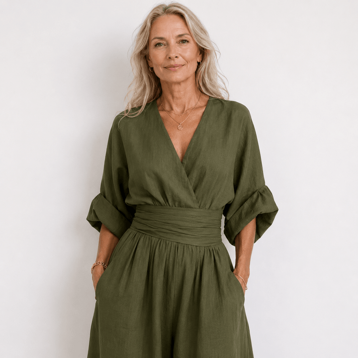 Middle-aged woman wearing an army green wrap jumpsuit with balloon sleeves and side pockets against a neutral background