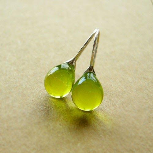 Vintage olive glass drop earrings with a polished finish on a neutral surface