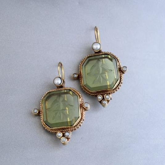 Vintage green drop earrings with pearl accents laid flat