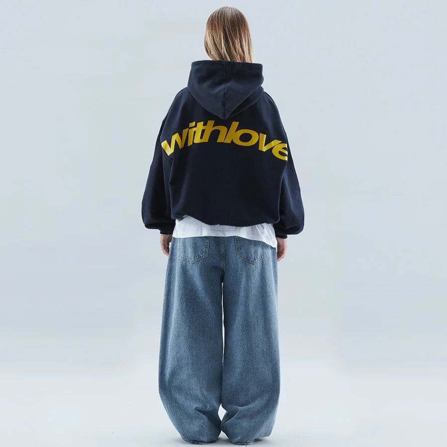 Model wearing a dark blue oversized graphic hoodie paired with loose denim trousers from behind
