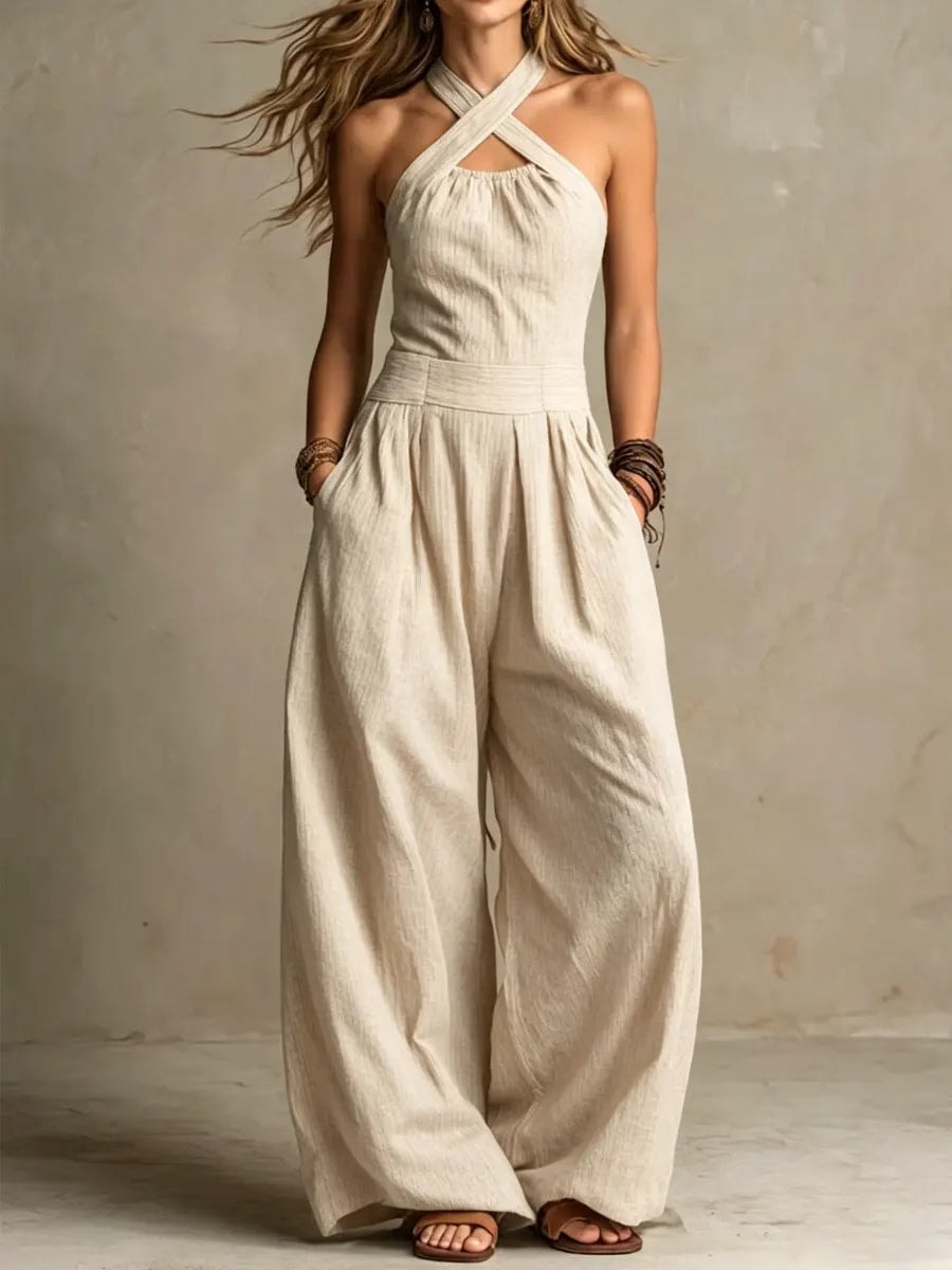 Woman wearing a beige cross-neck halter wide-leg jumpsuit in warm lighting