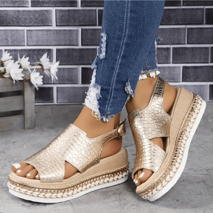 Side view of metallic gold orthopedic wedge sandals paired with distressed blue jeans
