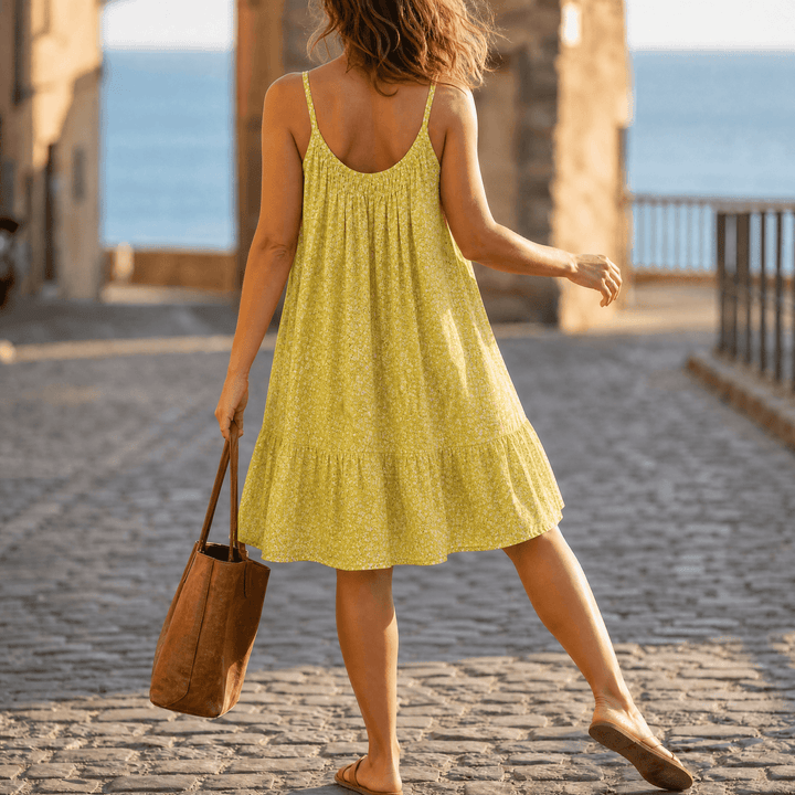 Woman wearing yellow floral swing mini summer dress from behind outdoors