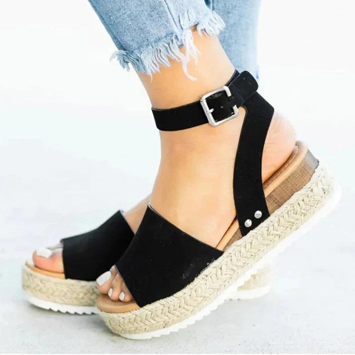Side view of women wearing black espadrille wedge sandals with buckle closure