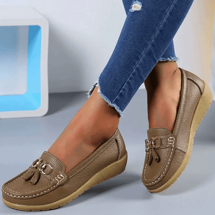Side view of khaki women's casual slip-on loafer shoes paired with blue jeans.