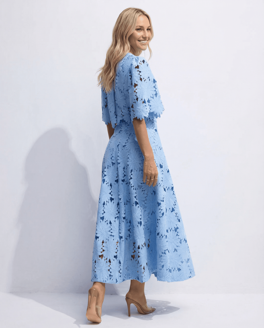Side angle view of a blonde model showcasing the flowing A-line midi skirt and matching lace top.