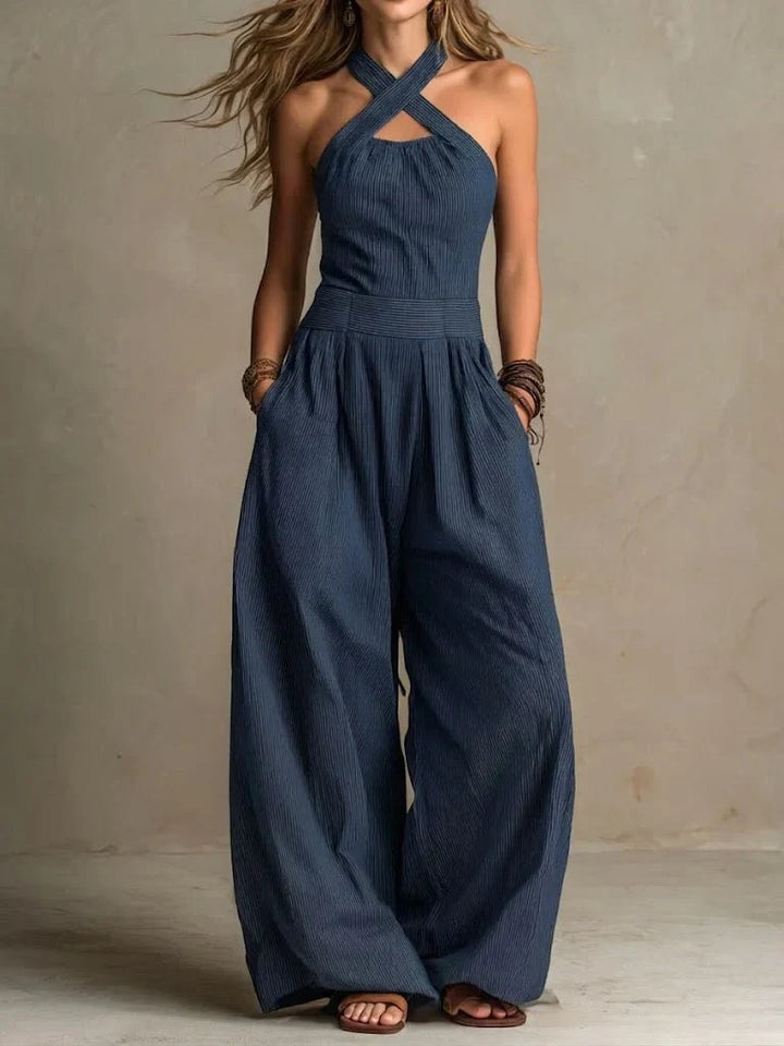 Woman wearing a navy blue cross-neck halter wide-leg jumpsuit outdoors
