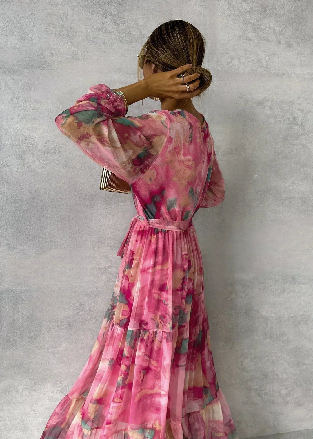 Back view of a model in a pink floral long sleeve wrap dress