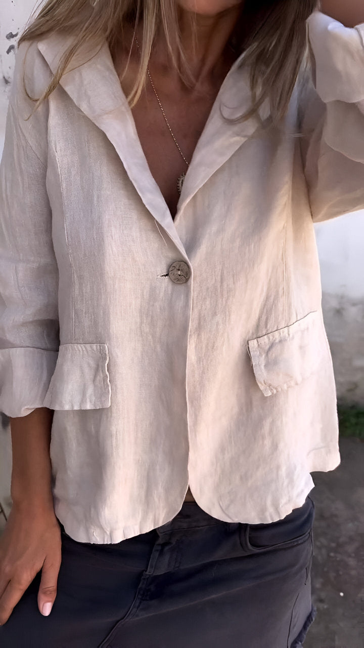 Woman wearing a neutral beige tailored jacket with single-button closure
