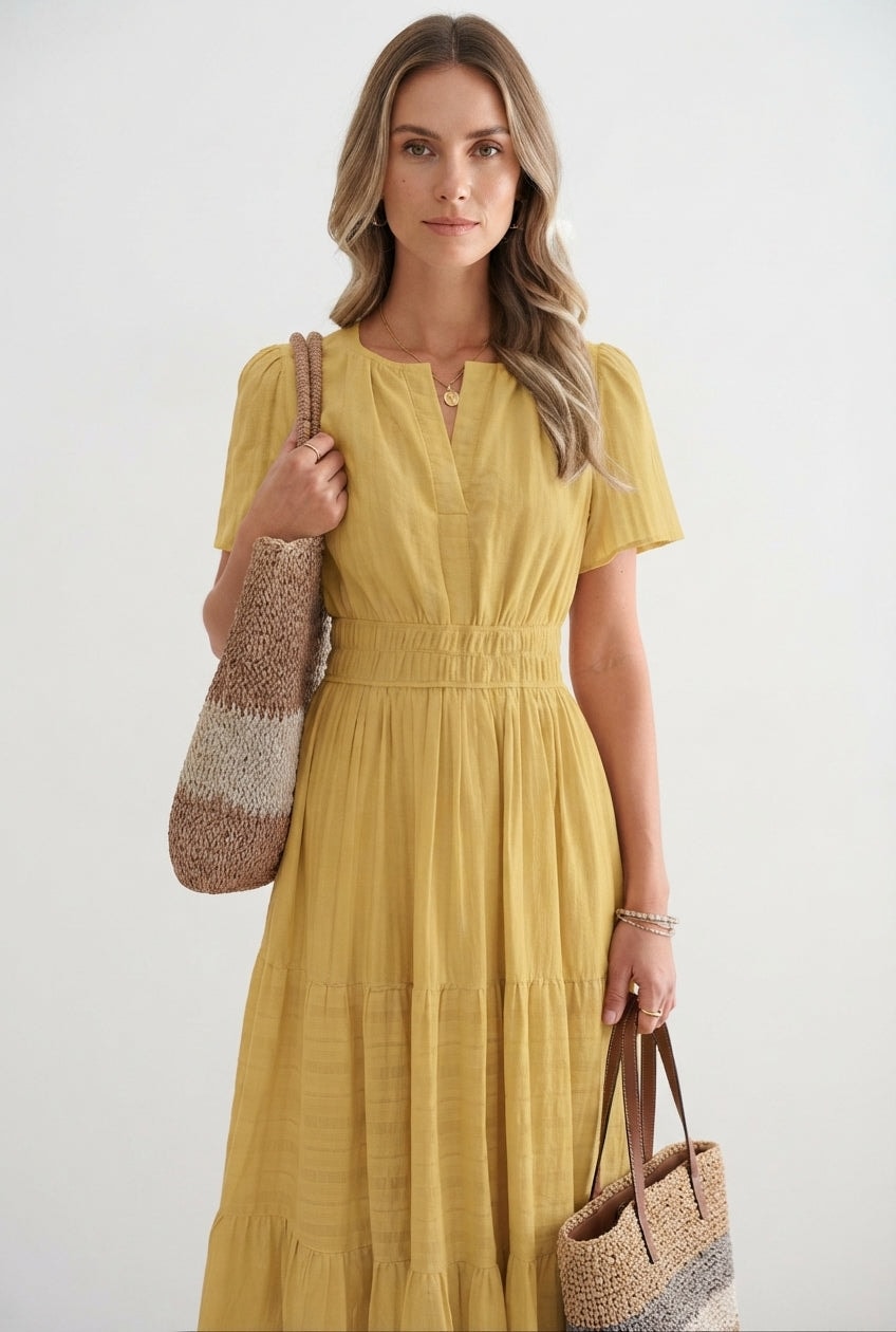 Close-up of model wearing a yellow tiered flutter-sleeve maxi dress with accessories
