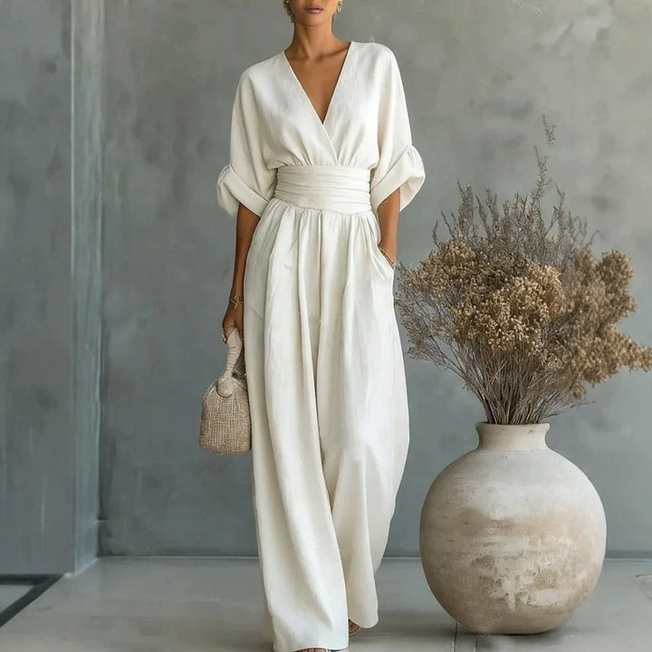 Elegant woman modeling a white wide-leg wrap jumpsuit with cuffed balloon sleeves and waist tie