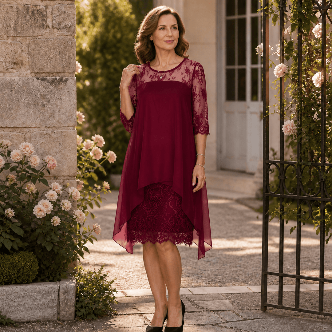 Full-length view of a woman standing by an iron gate in a burgundy lace party dress
