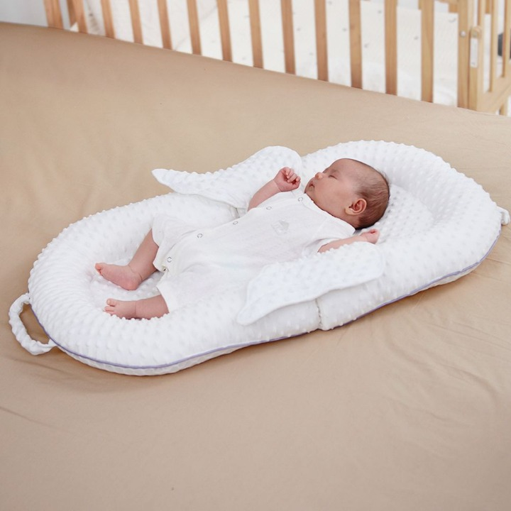 Baby resting comfortably in an ergonomic white lounger nest