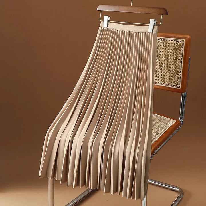 Light brown pleated midi skirt draped over a modern chair