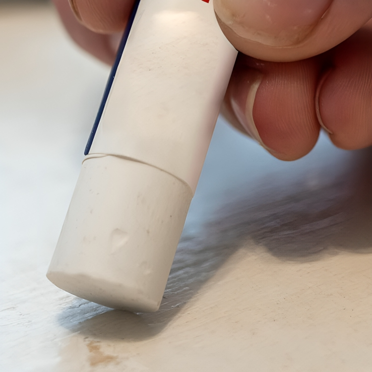 Close up of a white wood repair wax pen being applied to a surface