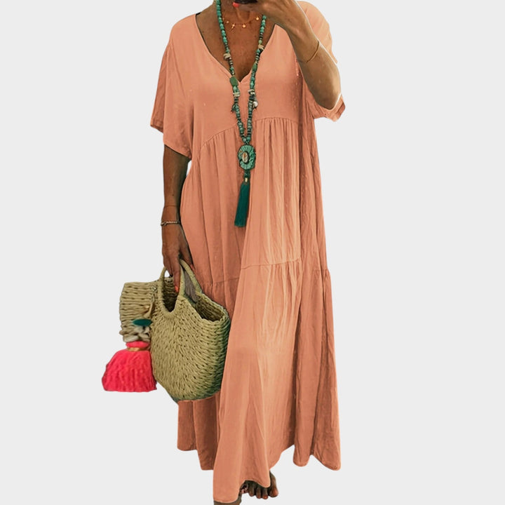 Woman wearing orange plus size maxi dress with V-neck and tiered skirt