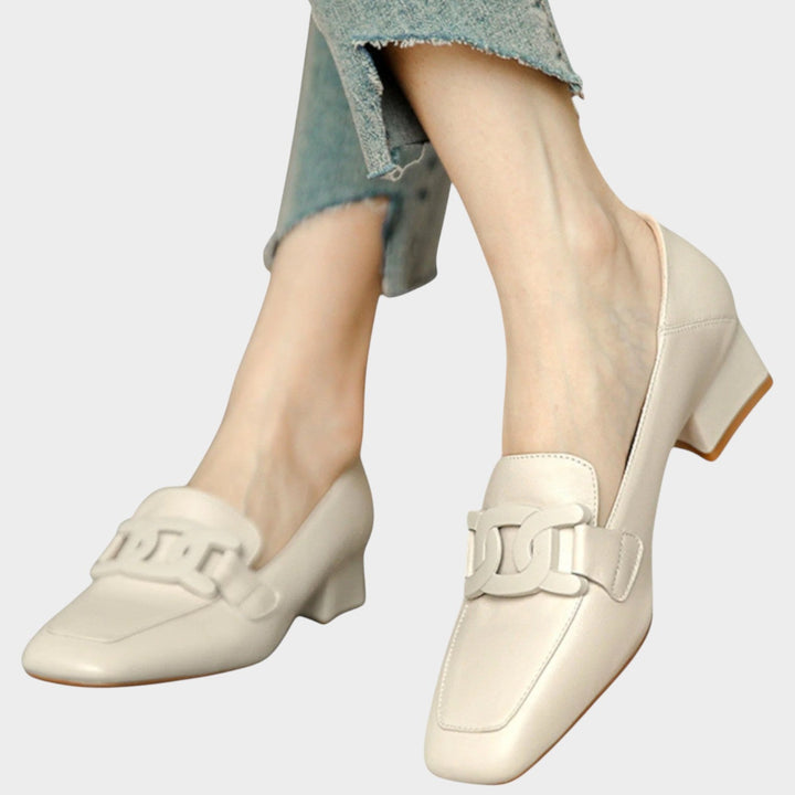 Side angle view of beige heeled loafers showcasing block heel and clean silhouette