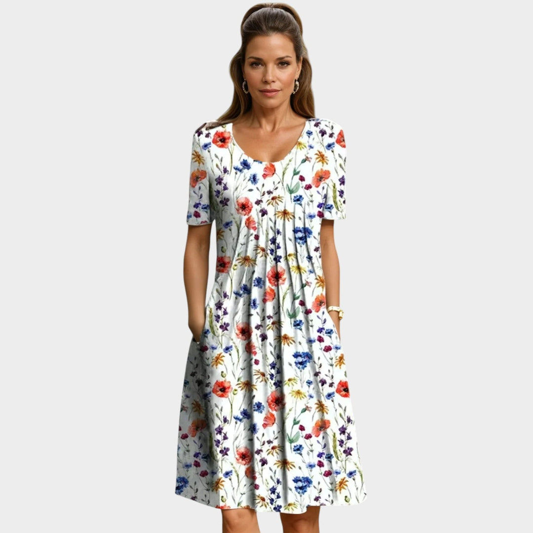 Woman wearing a white midi dress with red floral print and side pockets