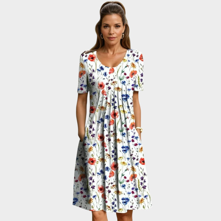 Woman wearing a white midi dress with red floral print and side pockets
