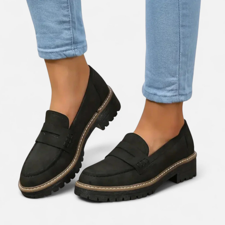 Black orthopedic heeled loafers worn with blue jeans