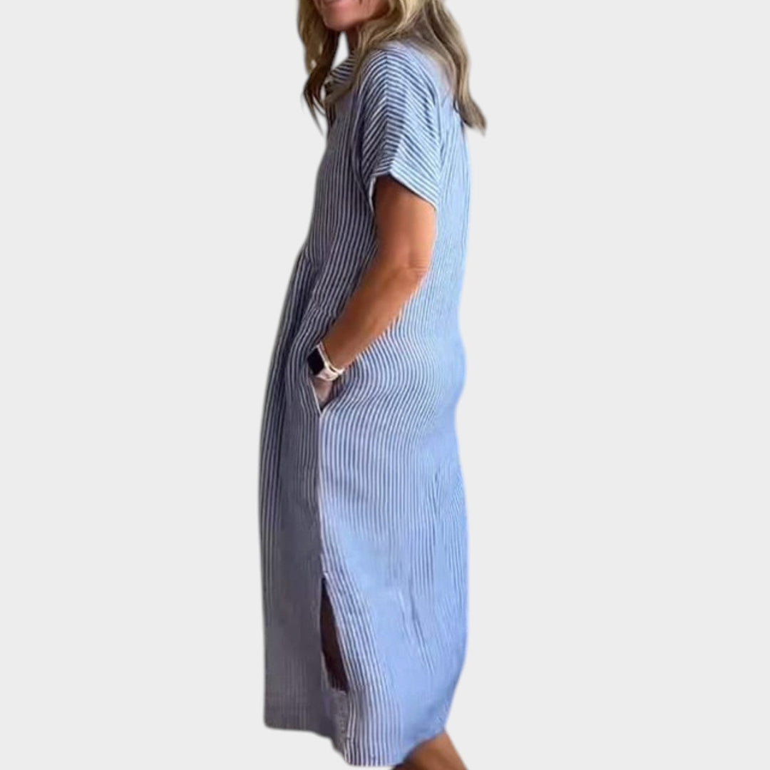 Side profile view of a woman wearing a blue striped maxi shirt dress with side slit