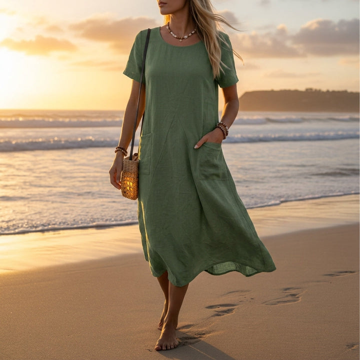 Woman wearing a sage green short sleeve pocket midi dress at the beach