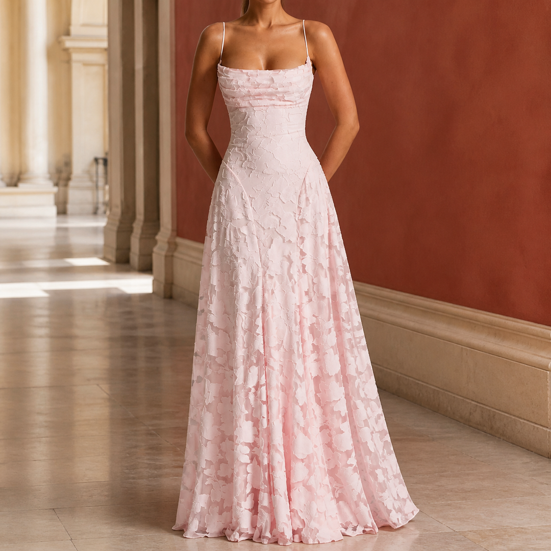 Woman wearing a pink draped cowl maxi dress with floral texture in a hallway