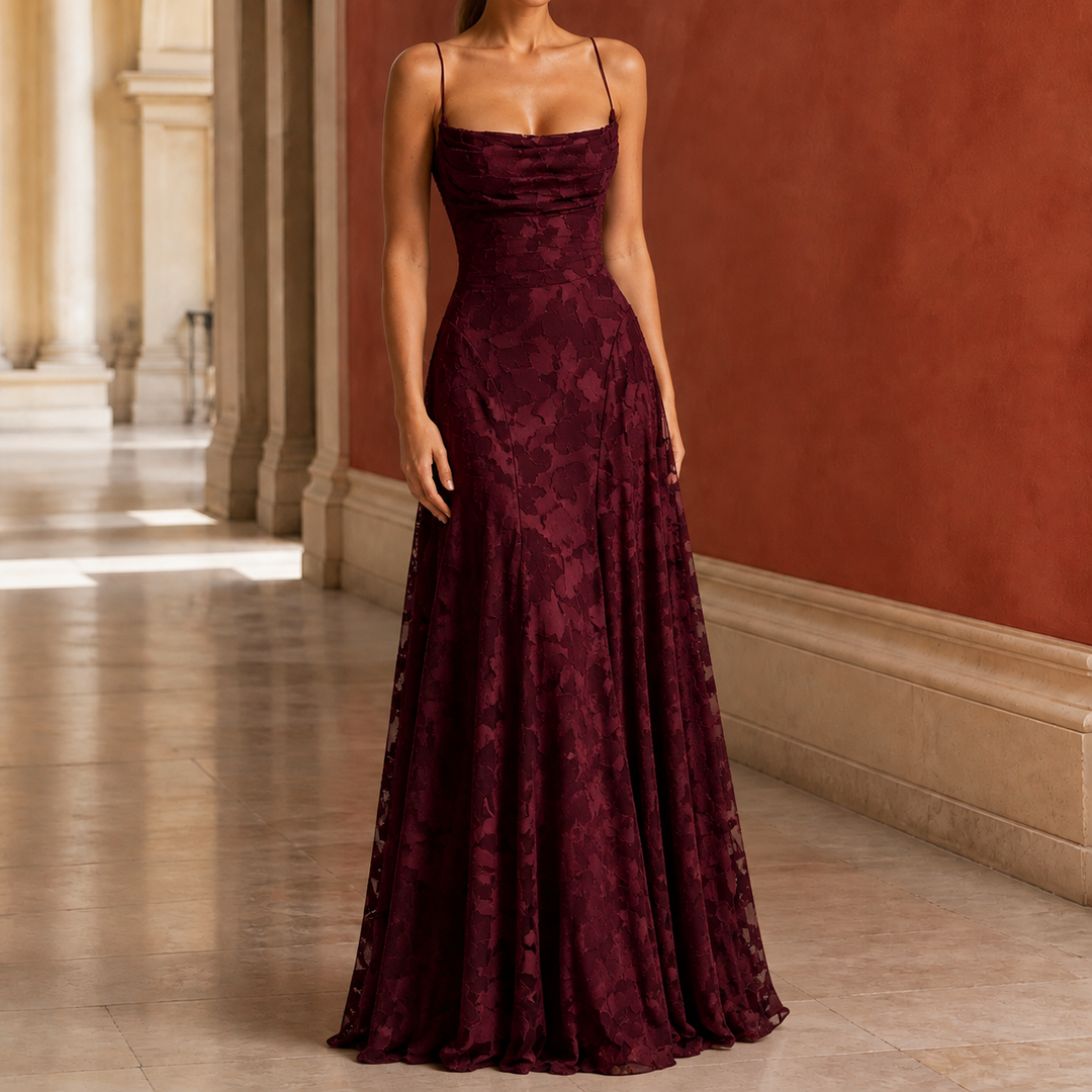 Woman wearing a burgundy draped cowl maxi dress with floral texture in a hallway