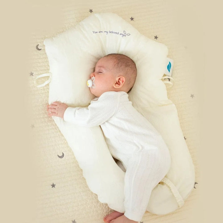Infant sleeping peacefully on an ergonomic support pillow with adjustable sides